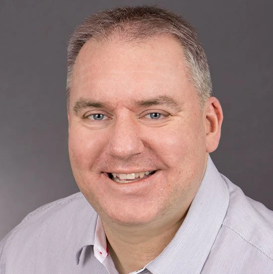 Porträt eines lächelnden Mannes im Hemd vor neutralem Hintergrund für Businessprofil.